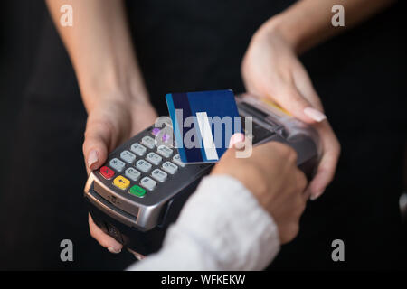 Les femmes paient par carte de crédit du client en attente d'utilisation de la technologie NFC sans contact Banque D'Images