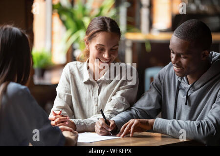 L'origine ethnique mixte clients heureux couple signe un contrat de prêt hypothécaire Banque D'Images