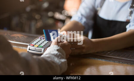 Female customer holding credit card près de la technologie NFC sur le comptoir Banque D'Images