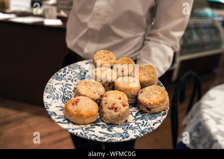 Un serveur sert des scones à la framboise au cours de thé l'après-midi Banque D'Images