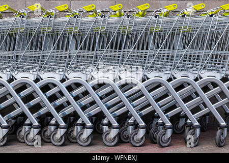 De nombreux chariots en acier gris avec poignées jaunes standing in a row comme fond pour shopping news sujets. Roues, partie inférieure, partie inférieure Banque D'Images