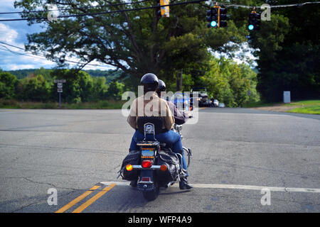 Storrs, CT USA. Aug 2019. Couple on motorcycle faire un virage à gauche à une intersection lors d'une tournée de la Nouvelle Angleterre. Banque D'Images