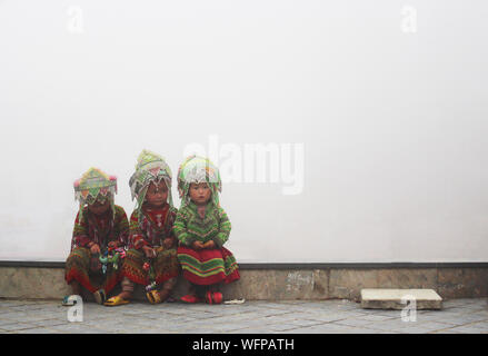 Sapa, Vietnam - 4 juin 2019 - les petites filles dans des vêtements hmong traditionnelle assise sur le bord d'un très soir brumeux Banque D'Images