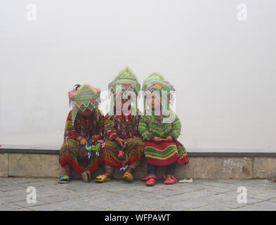 Sapa, Vietnam - 4 juin 2019 - les petites filles dans des vêtements hmong traditionnelle assise sur le bord d'un très soir brumeux Banque D'Images