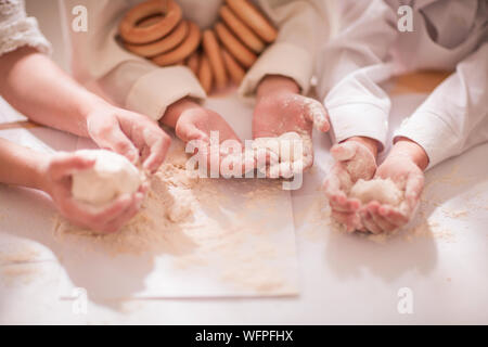 Mains close-up avec la pâte et la farine, heureux petits enfants sous la forme d'un chef pour cuisiner un délicieux Banque D'Images