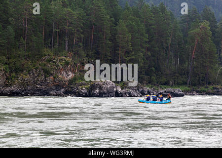 Une équipe d'athlètes dans un bateau gonflable bleu radeaux d'une montagne au milieu d'une rivière de la forêt verte et les montagnes.rafting sur une rivière de montagne Banque D'Images