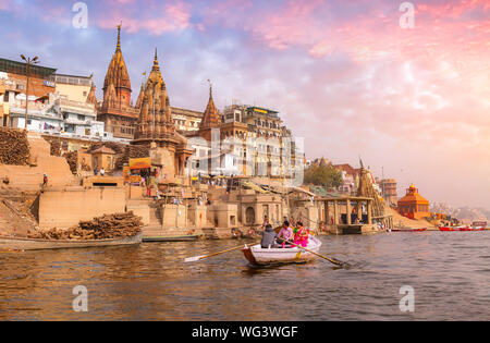 Gange ghat Varanasi Inde avec des touristes indiens bénéficiant en bateau sur la rivière au coucher du soleil Banque D'Images