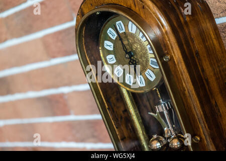 Un gros plan d'une antique horloge en bois doré avec mur de brique Banque D'Images