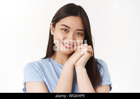 Close-up silly jolie fille asiatique romantique gaie tendresse sentiment sentiments réconfortants tenir la main près de joues soupirant smiling ravis le regard Banque D'Images