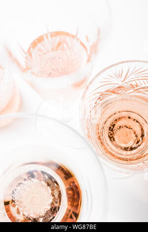 Vin rose pétillant dans différents verres sur fond blanc Banque D'Images