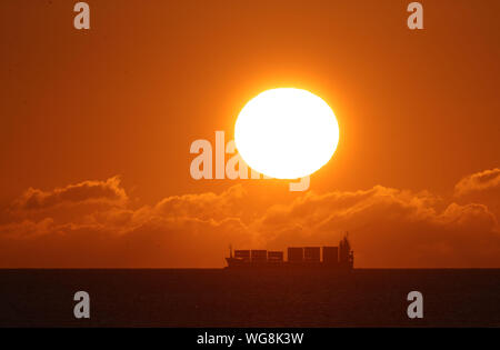 Un cargo à l'horizon comme le soleil se lève à Seahouses sur le Nord de la côte de Northumberland. Banque D'Images