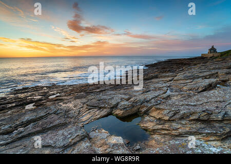 Le lever du soleil sur la côte rocheuse à Howick sur la côte de Northumberland Banque D'Images