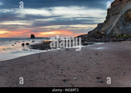 Lever du soleil à Saltwick Bay sur la côte près de Whitby, North Yorkshire Banque D'Images