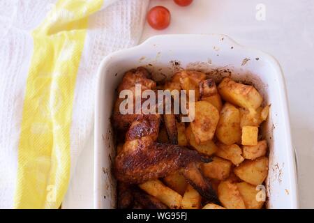 Ailes de poulet épicées délicieuses pommes de terre rôties et servi au fond en bois Banque D'Images