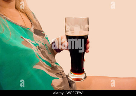 Boissons bière brune fille. Close up aucun droit de femme d'âge moyen avec verre au bar ou au pub. Visiteuse est titulaire d'une goélette avec de la bière fraîche Banque D'Images