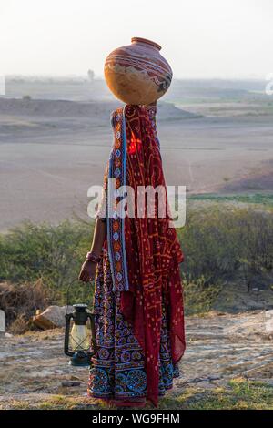 Woman in traditional Ahir vêtements colorés portant de l'eau dans une cruche d'argile sur la tête, Grand Rann de Kutch, Gujarat, Inde Banque D'Images