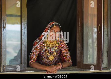 Ahir femme en vêtements colorés traditionnels à la recherche d'une fenêtre, Grand Rann de Kutch, Gujarat, Inde Banque D'Images