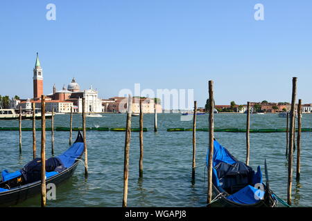 En vue de face deux gondoles amarrées sur les poteaux d'amarrage sur le quai San Marco Square. Historique l'église San Giorgio Maggiore Grand Canal Venise Italie Banque D'Images