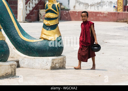 Inle, Myanmar - Avril 2019 : moine birman balade dans le monastère cour avec bol de riz dans ses mains Banque D'Images