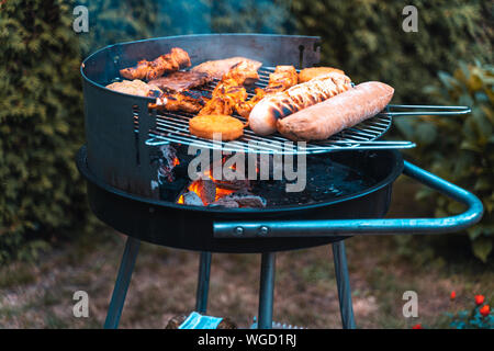 Temps tours un barbecue avec différentes sortes de viande. Placé sur l'herbe.. Banque D'Images