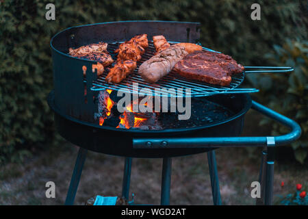 Temps tours un barbecue avec différentes sortes de viande. Placé sur l'herbe.. Banque D'Images