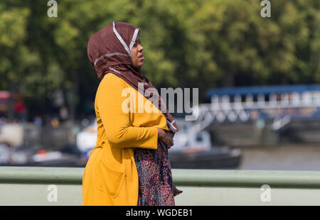 Vue latérale d'une jeune femme, peut-être du Moyen-Orient, portant un foulard ou une couverture de tête hijab souvent portée par des femmes musulmanes en été à Londres, au Royaume-Uni. Banque D'Images