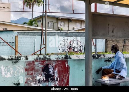 Un homme âgé assis sur un banc en regardant les murs couverts de graffitis, Trinité-et-Tobago Banque D'Images