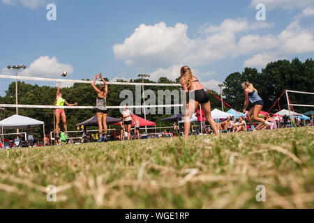 Faible angle plan large montre le volleyball féminin joueurs participant à un tournoi de volley-ball de l'herbe tripler le 25 août 2019 à Doraville, Géorgie. Banque D'Images