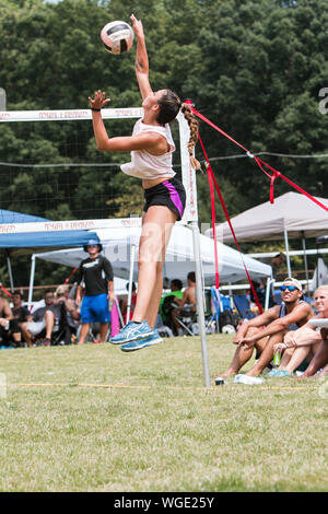 Une femme saute haut pour spike ball dans un tournoi de volley-ball à herbe triples Honeysuckle Park le 25 août 2019 à Doraville, Géorgie. Banque D'Images