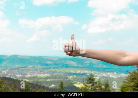 Main montre Thumbs up sur l'arrière-plan de montagnes Banque D'Images