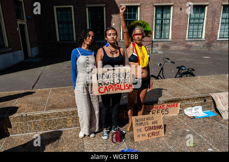 Trois femmes brésiliennes portant des vêtements autochtones posent tout en tenant une pancarte, pendant la manifestation.Brésiliens vivant dans les Pays-Bas ont organisé une manifestation de solidarité avec les protecteurs de la forêt et contre le président du Brésil, Jaïr. Bolsonaro Autour de cinquante personnes se sont réunies à La Haye pour montrer leur soutien. Banque D'Images