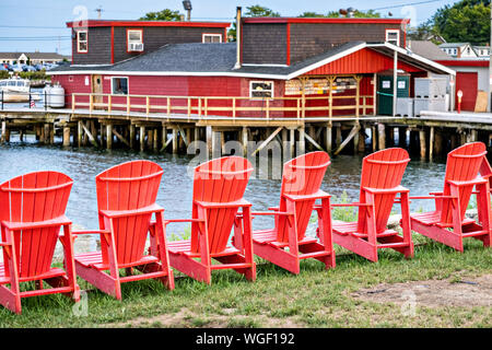 Adirondack chaises rouges alignés à l'extérieur de Cook's Lobster Wharf sur l'île, l'ORRS au Maine. Banque D'Images