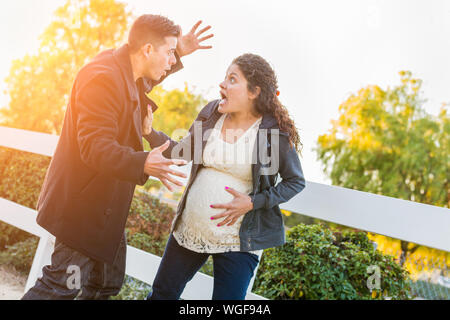 Jeune couple enceinte hispanique assommé dans la douleur la marche à l'extérieur. Banque D'Images