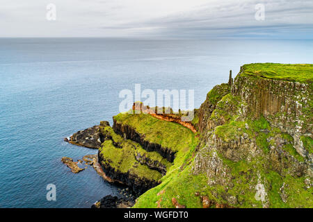 L'Irlande du Nord, Royaume-Uni. Falaises de la côte atlantique dans le comté d'Antrim avec strates géologiques visibles, et formation de basalte volcanique naturel de pol hexagonale Banque D'Images