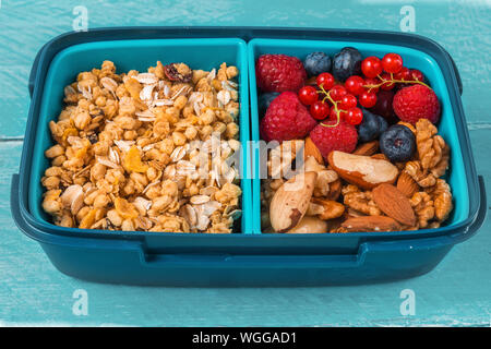 École en santé boîte à lunch avec granola, noix et baies de prendre un petit-déjeuner sain on blue background. close up Banque D'Images