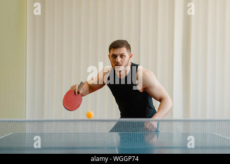Homme avec raquette et balle de ping-pong jouer à l'intérieur Banque D'Images