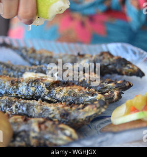 Lison, Portugal : un diner tire le jus de citron sur des sardines grillées Banque D'Images