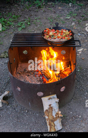 Le dîner la cuisson à feu ouvert poêle en fonte camping le bacon et les légumes Banque D'Images