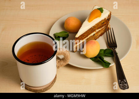 Plaque avec gâteau de carotte et d'abricot se distingue avec une tasse de thé sur une table en bois clair. Banque D'Images