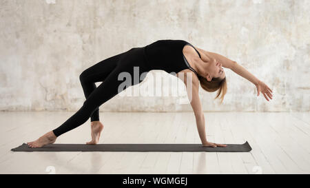 Woman practicing yoga, debout dans l'article de la chose, Camatkarasana Banque D'Images