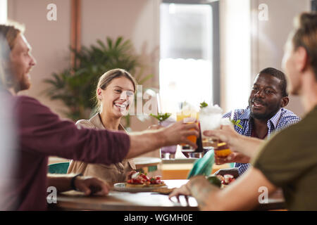 Multi-ethnic group of friends clinking glasses while sitting at table in cafe froid profiter de boissons rafraîchissantes, copy space Banque D'Images