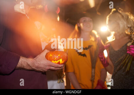 De gros plan homme méconnaissable holding carved pumpkin tout en profitant d'Halloween dans une boîte de nuit, l'arrière-plan de l'espace de copie Banque D'Images