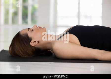 Jeune femme aux yeux clos pratiquant le yoga, Savasana, Cadavre poser Banque D'Images