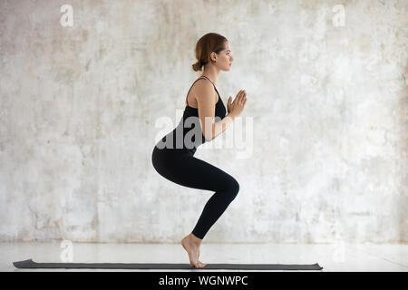 Jeune femme pratiquant le yoga, faire de l'exercice, Président Utkatasana poser Banque D'Images