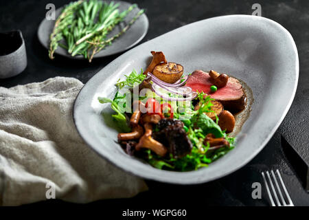 Tagliata de boeuf avec légumes. Close-up, clé faible, fond gris Banque D'Images