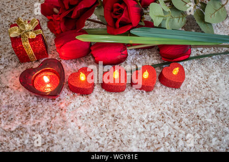 Tulipes, roses et fleurs bougie en forme de coeur sur la neige comme un arrière-plan. Concept de la Saint Valentin. Banque D'Images