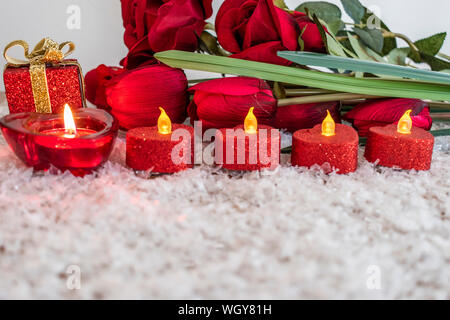 Tulipes, roses et fleurs bougie en forme de coeur sur la neige comme un arrière-plan. Concept de la Saint Valentin. Banque D'Images