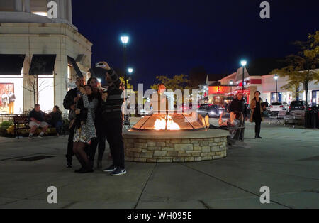 South Windsor CT USA. Nov 2018. Famille à la nuit qui pose en tenant vos autoportraits avec ice cream cones par un joli feu chaud à un centre commercial extérieur. Banque D'Images