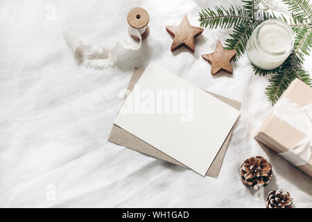 Composition de Noël. Carte de voeux vierge, enveloppe maquette des lieux. Coin décoratif. Pommes de Pin, branches de sapins, boîte-cadeau en bois et étoiles sur whi Banque D'Images