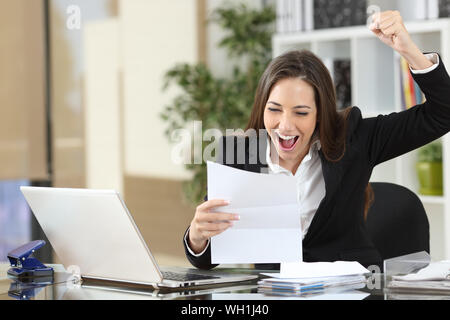 Heureux businesswoman reading bonne nouvelle en lettre sitting at office Banque D'Images